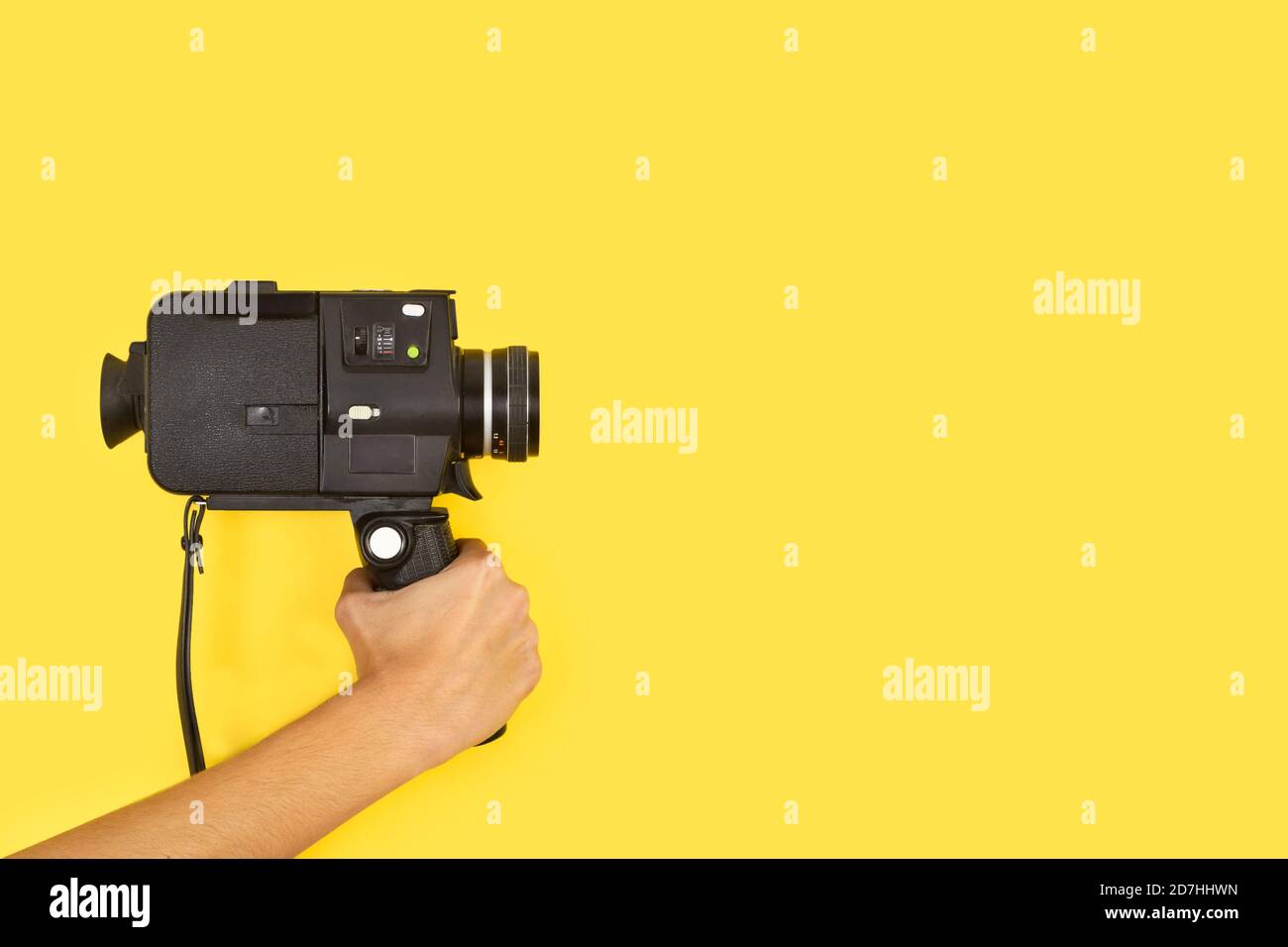 Frau, die eine Kamera mit acht Millimetern auf einem gelben Hintergrund hält Mit Kopierbereich Stockfoto