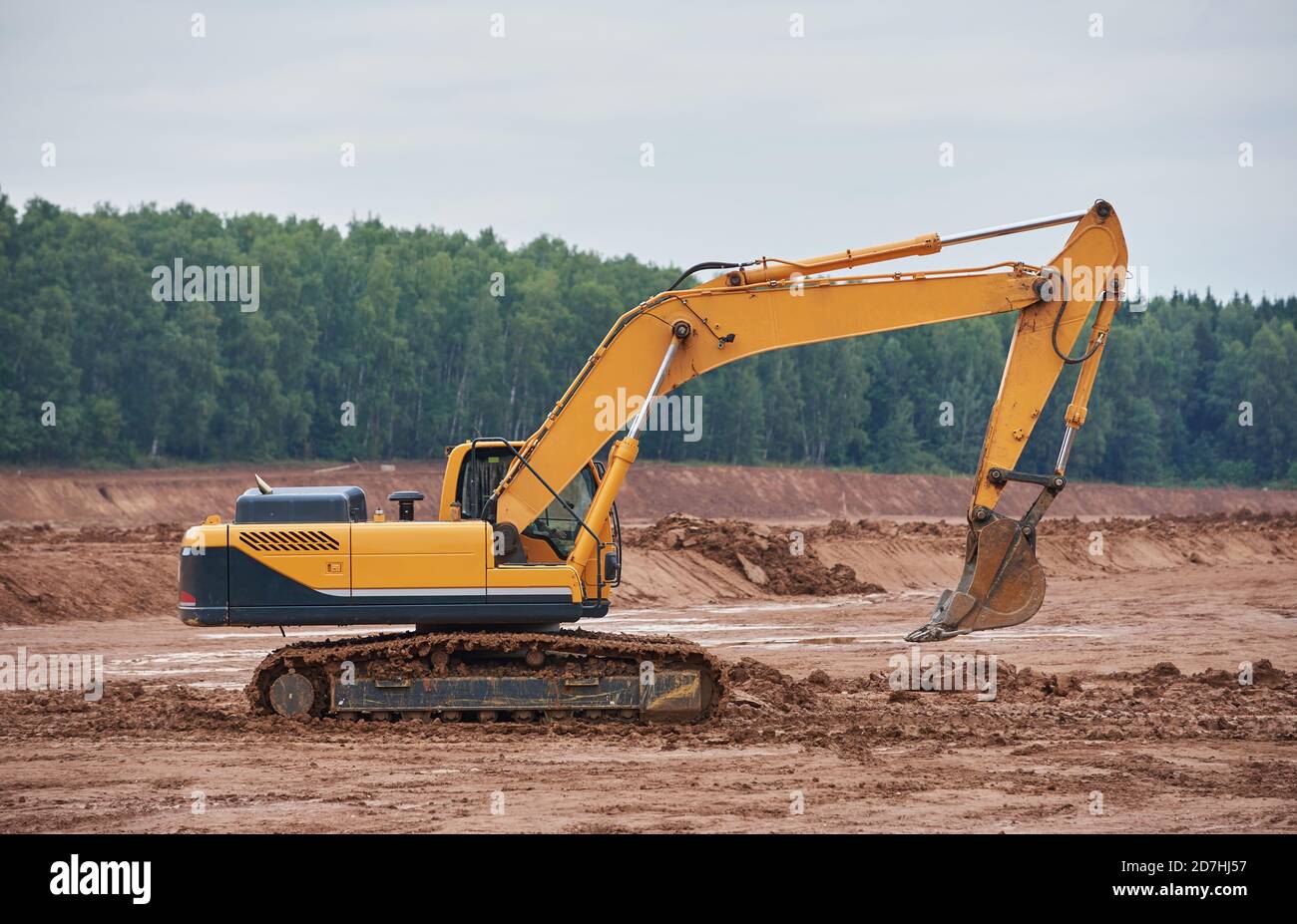 Der moderne Raupenbagger fährt durch ein schlammiges Feld Stockfoto