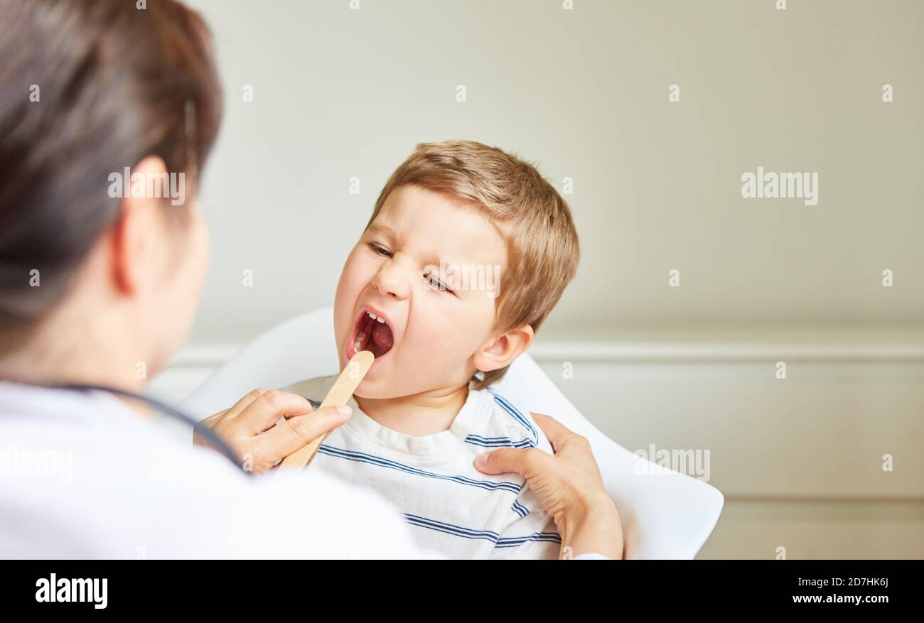 Kinderarzt untersucht Kind mit Mandelentzündung oder Halsschmerzen mit Spatel Stockfoto