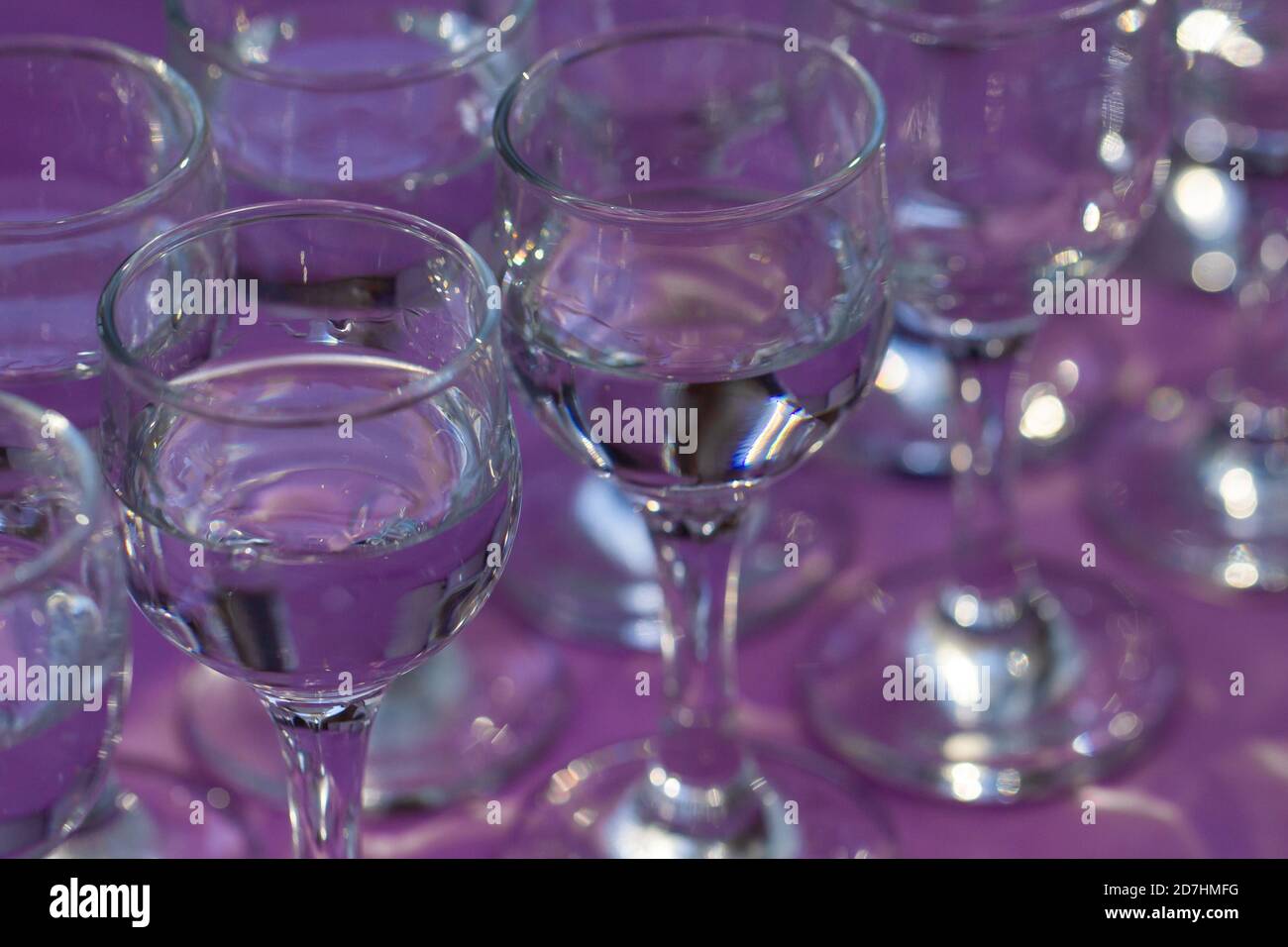 Elegante Wassergläser auf violettem Tisch serviert, Nahaufnahme, Draufsicht Stockfoto