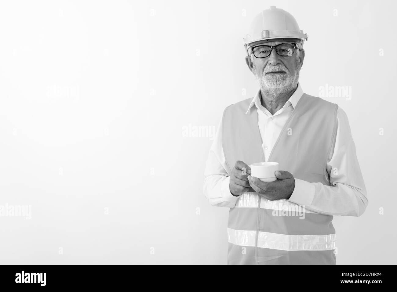 Studio geschossen von Stattlichen älteren bärtigen Mann Bauarbeiter holding Kaffeetasse beim Tragen von Brillen vor weißem Hintergrund Stockfoto