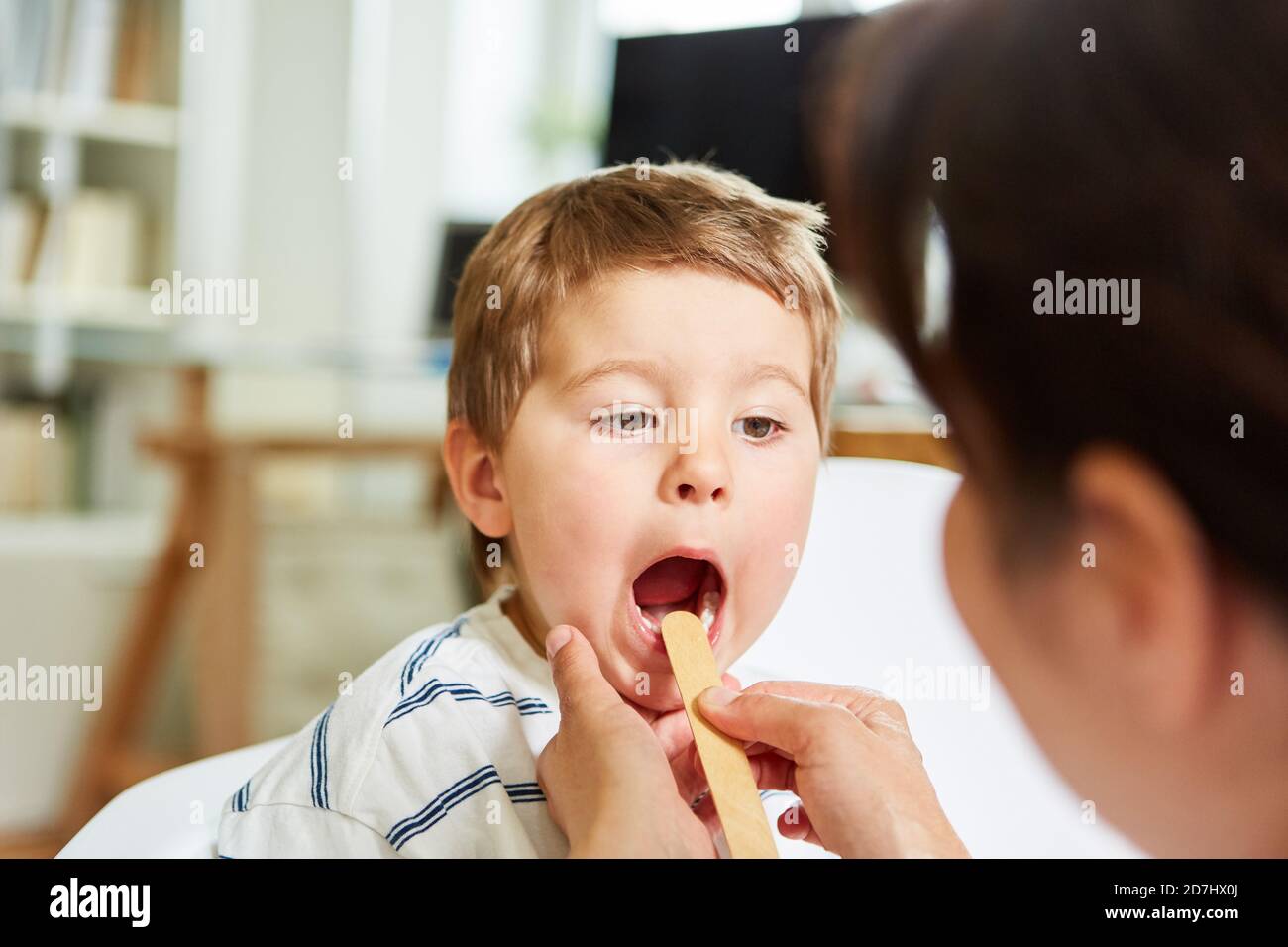 Kinderarzt mit Spatel untersucht Kind mit Mandelentzündung und Halsschmerzen Stockfoto