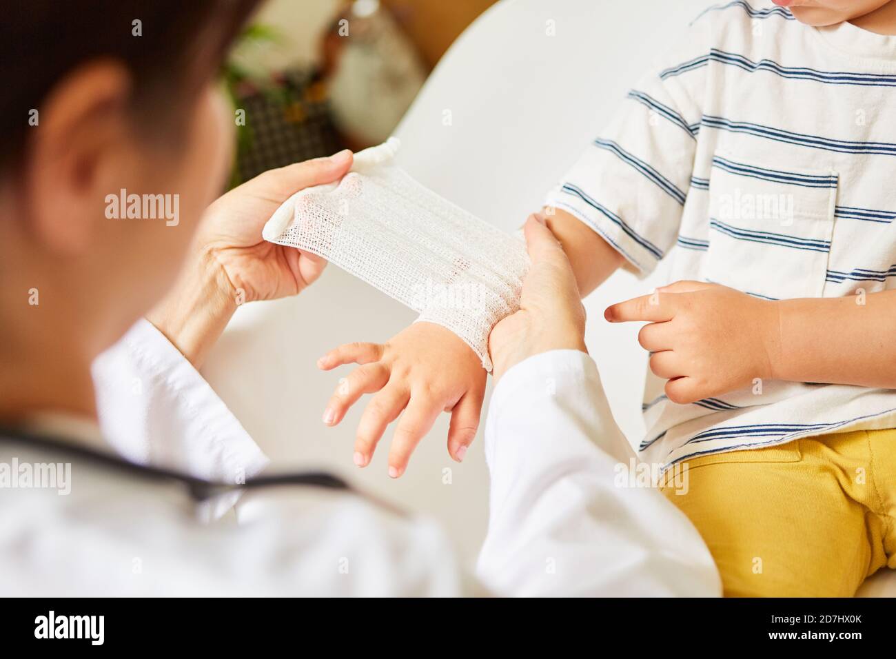 Kinderarzt wickelt Verband um das Handgelenk des Kindes im Falle von Eine Verstauchung oder ein Unfall Stockfoto