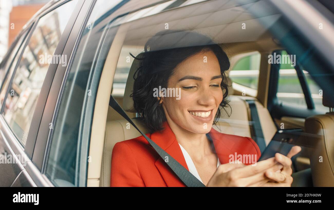Schöne Frau Reisen in einem Auto, sitzen auf einem Beifahrersitz verwendet Smartphone, Typen Nachricht, browses through Internet. Kamera Aufnahme von außerhalb des Stockfoto