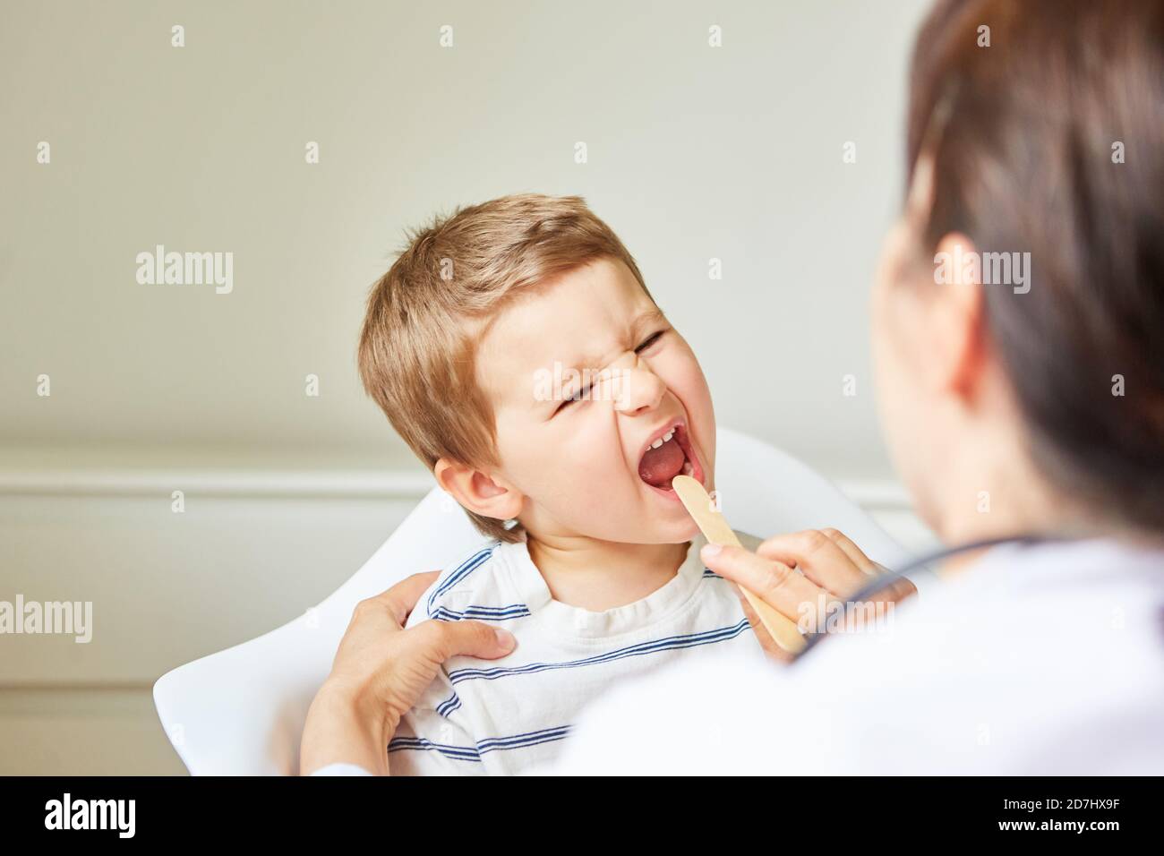 Kinderarzt untersucht Kind mit Halsschmerzen oder Mandelentzündung mit Spatel Stockfoto