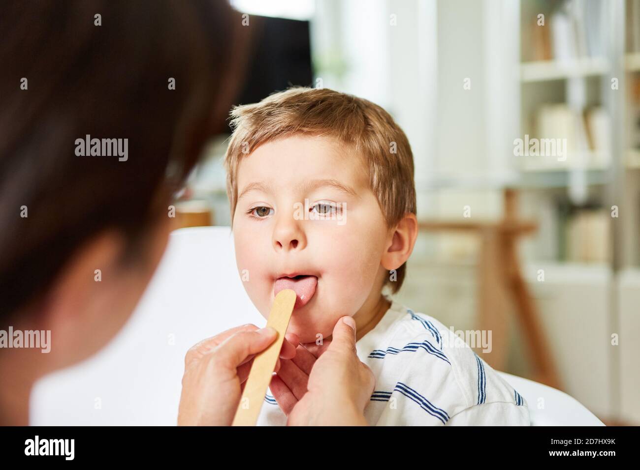 Kind mit Halsschmerzen bei der Untersuchung durch den Kinderarzt mit dem Spatel Stockfoto