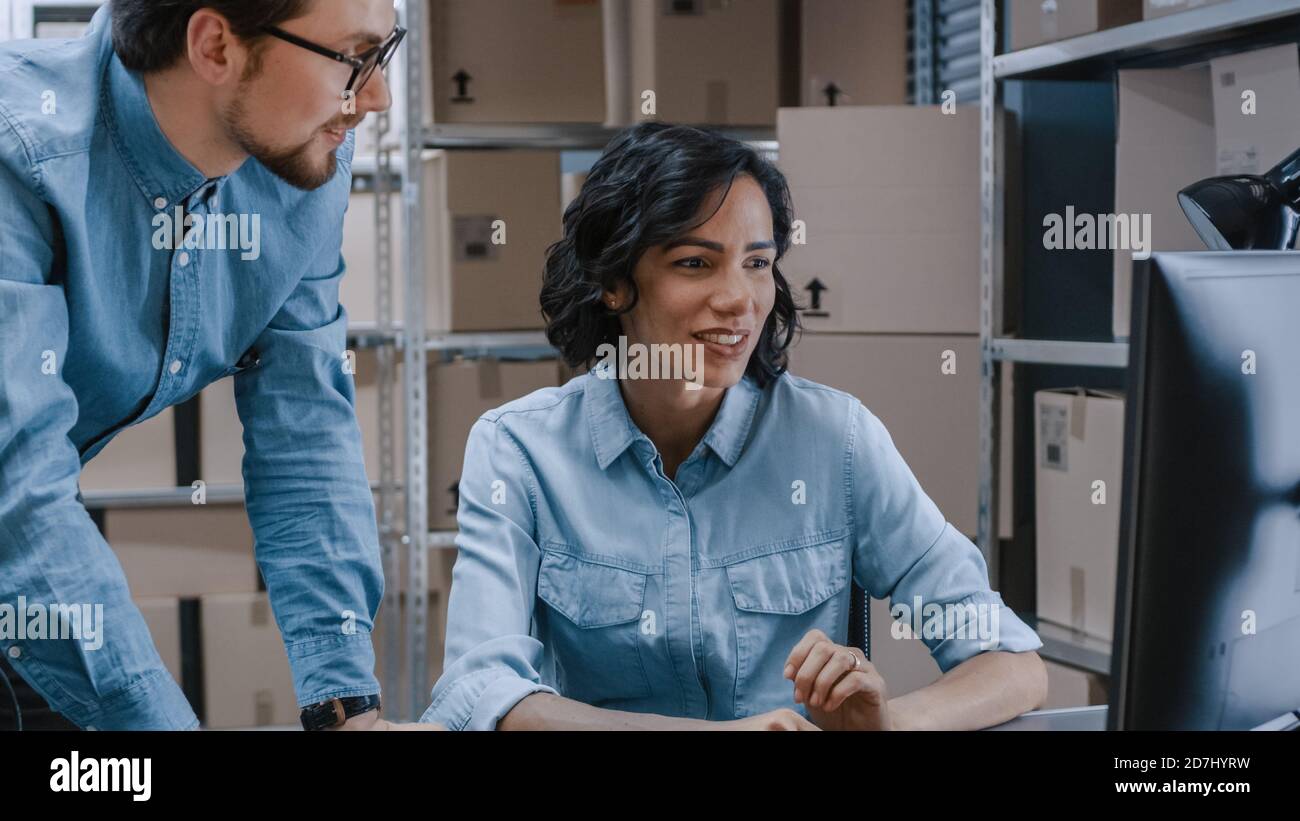 Männliche und weibliche Lagerbestandsmanager sprechen, Probleme lösen, Personal-Computer verwenden und Bestand überprüfen. In den Regalen im Hintergrund Stockfoto