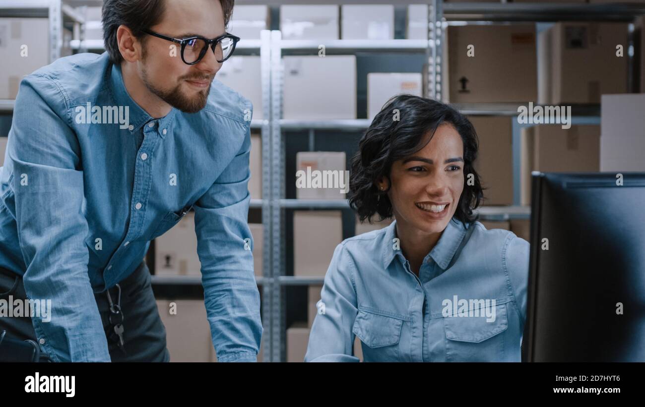 Männliche und weibliche Lagerbestandsmanager sprechen, Probleme lösen, Personal-Computer verwenden und Bestand überprüfen. In den Regalen im Hintergrund Stockfoto