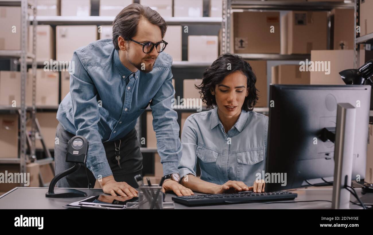 Männliche und weibliche Lagerbestandsmanager sprechen, Probleme lösen, Personal-Computer verwenden und Bestand überprüfen. In den Regalen im Hintergrund Stockfoto