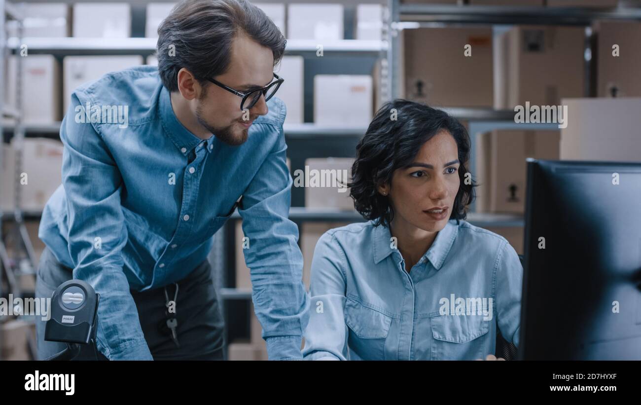 Männliche und weibliche Lagerbestandsmanager sprechen, Probleme lösen, Personal-Computer verwenden und Bestand überprüfen. In den Regalen im Hintergrund Stockfoto