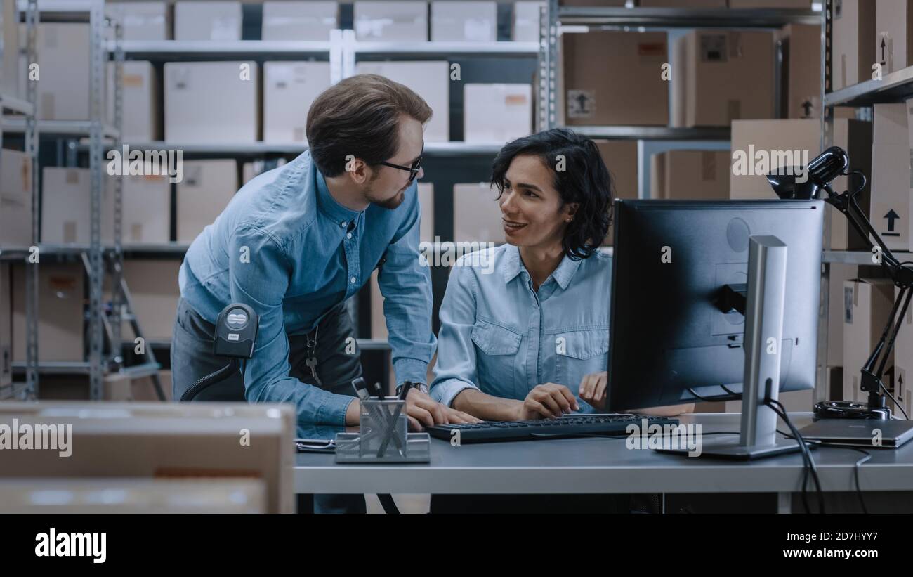 Männliche und weibliche Lagerbestandsmanager sprechen, Probleme lösen, Personal-Computer verwenden und Bestand überprüfen. In den Regalen im Hintergrund Stockfoto
