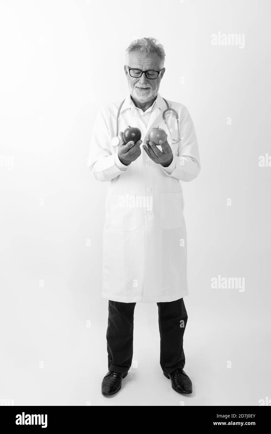 Ganzkörperaufnahme eines gutaussehenden älteren bärtigen Mannes, Doktor stehend Während Sie zwei Äpfel halten Stockfoto