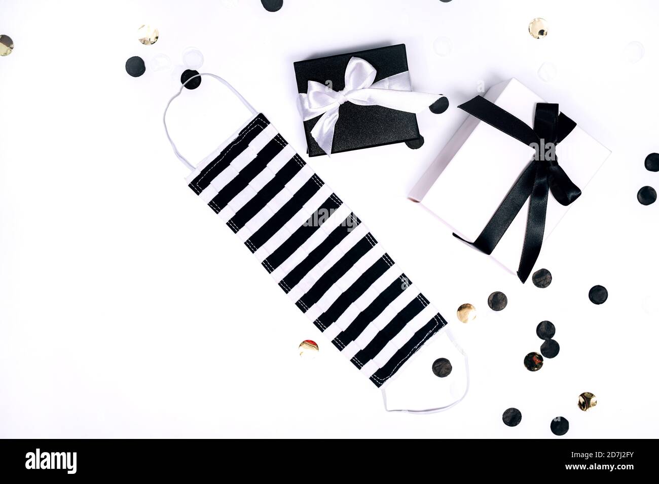 Schwarz-weiße Geschenk- oder Geschenkschachteln, handgemachte Gesichtsmaske und Konfetti auf weißem Hintergrund. Flache Lay-Komposition für Geburtstag, Weihnachten, Hochzeit. Soziale Gespiede. Stockfoto