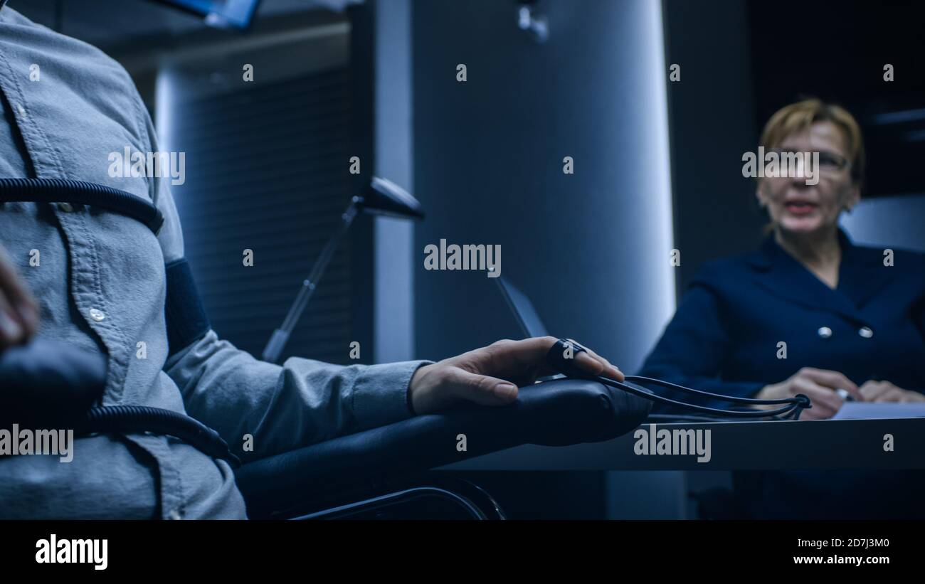 Weiblicher Spezialagent führt einen Lügendetektor-Polygraphen-Test bei einem anonymen Verdächtigen durch. Sachverständiger Prüfer Fragen im Verhörraum angeklagt. Computer Stockfoto