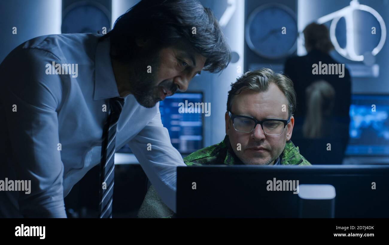 Der Regierungsleiter des Cyber Security Agent berät den Militärbeauftragten, der am Computer arbeitet. Spezialisten, die an Computern im Systemkontrollraum arbeiten. Stockfoto