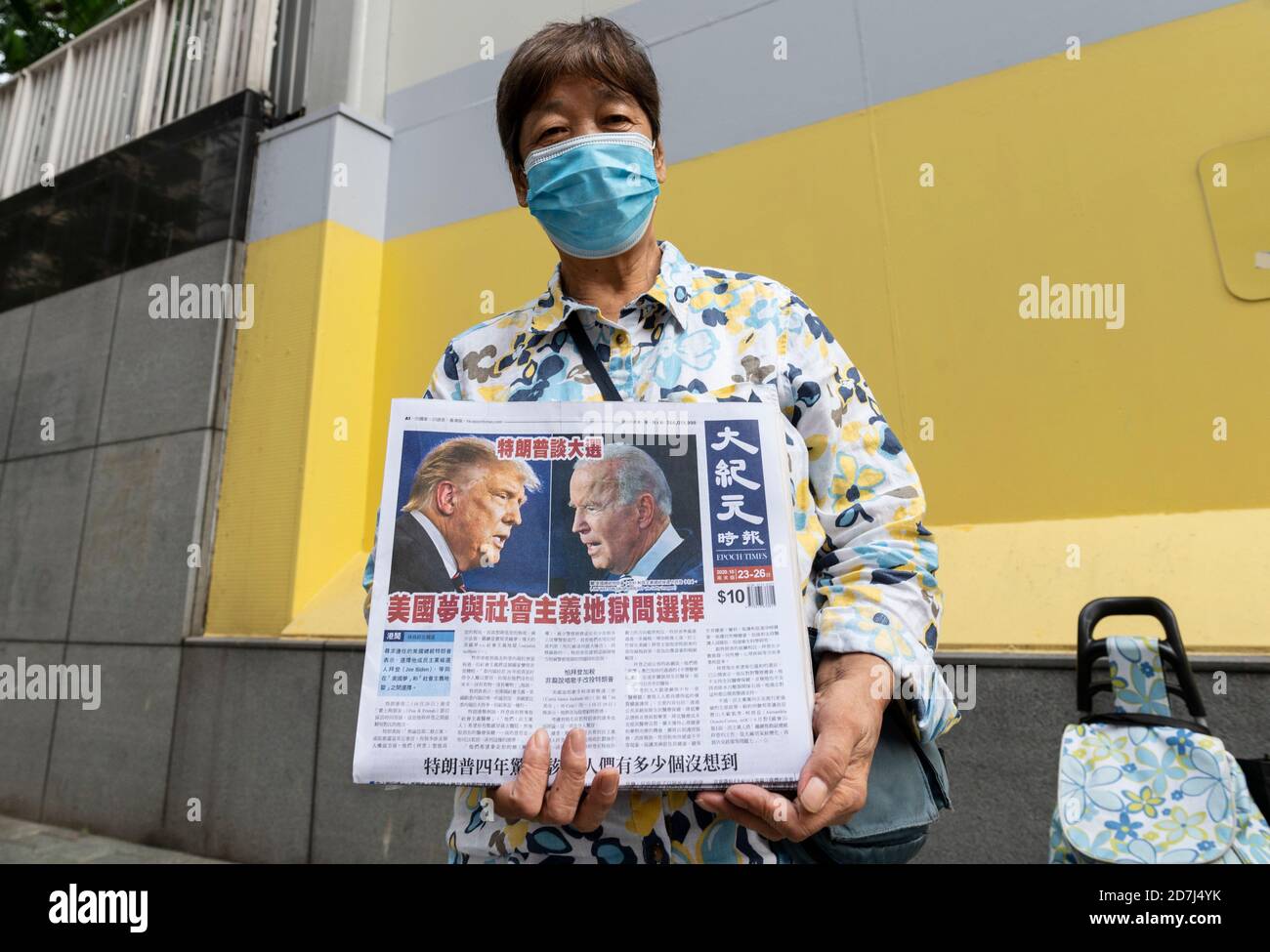 Eine Frau trägt eine Gesichtsmask verteilt die mehrsprachige Zeitung The Epoch Times, die die US-Wahldebatte zwischen Donald J. Trump und Joe Biden zeigt. Stockfoto