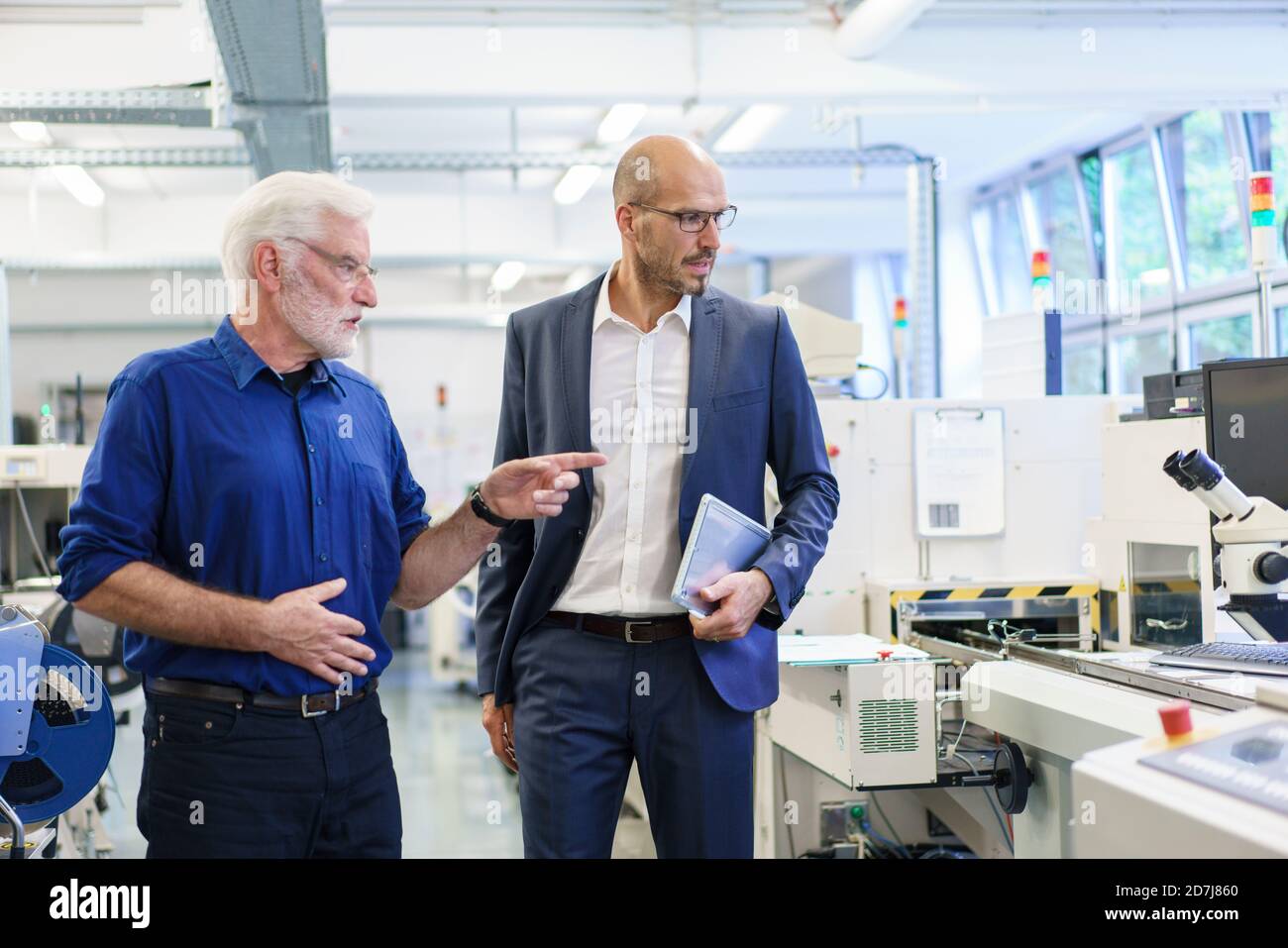 Leitender männlicher Manager zeigt beim Gespräch mit einem Kollegen im Labor Stockfoto