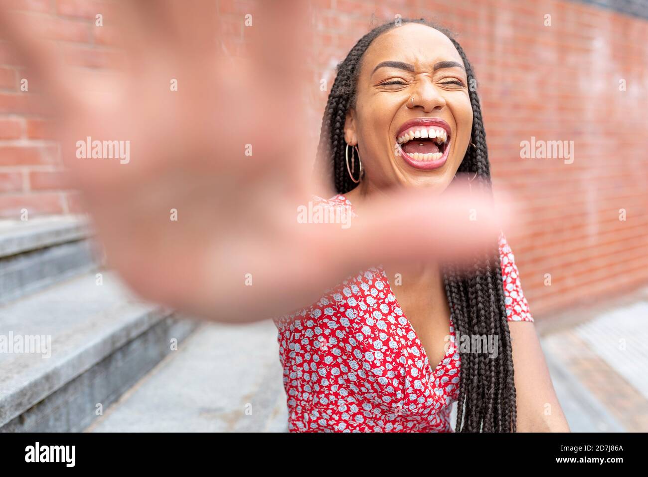 Frau zeigt Stop-Geste, während sie auf der Treppe in der Stadt sitzt Stockfoto