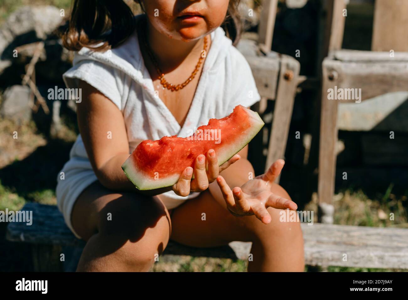 Mädchen essen Wassermelone während sitzen auf log Stockfoto