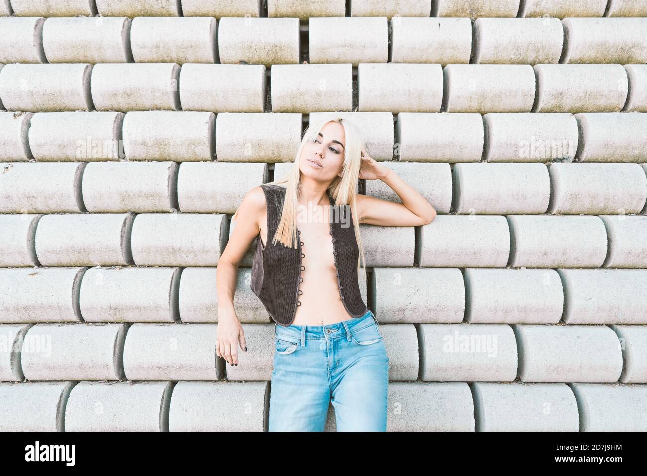 Nachdenkliche junge Frau trägt Jacke, die gegen Steinwand steht Stockfoto