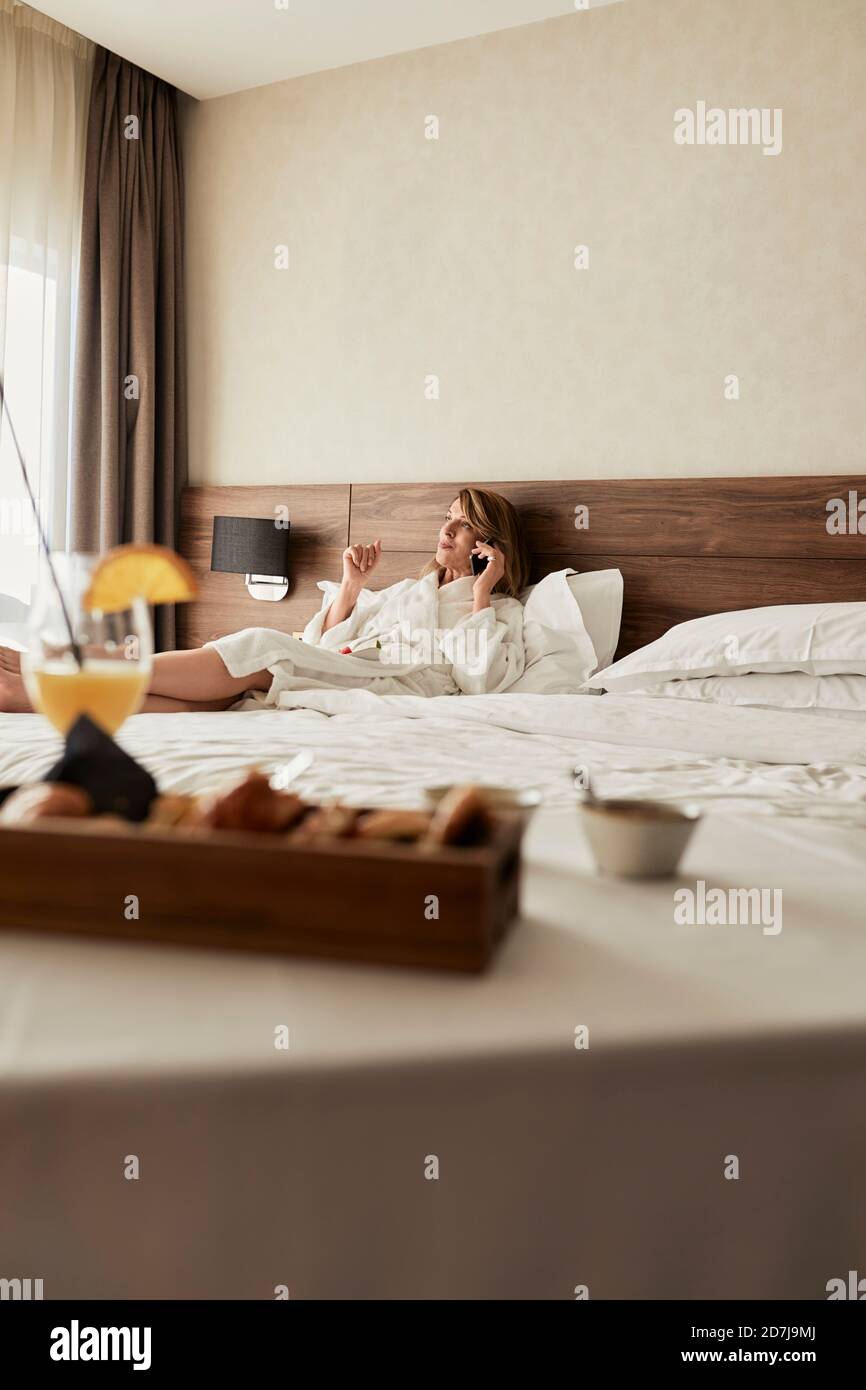 Frühstück gegen eine Frau, die sich auf dem Sofa im Hotel unterhielt Zimmer Stockfoto