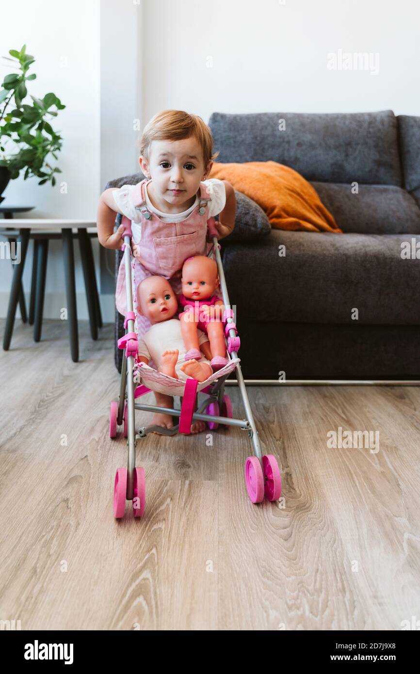 Baby Mädchen spielen mit Baby Kinderwagen zu Hause Stockfoto