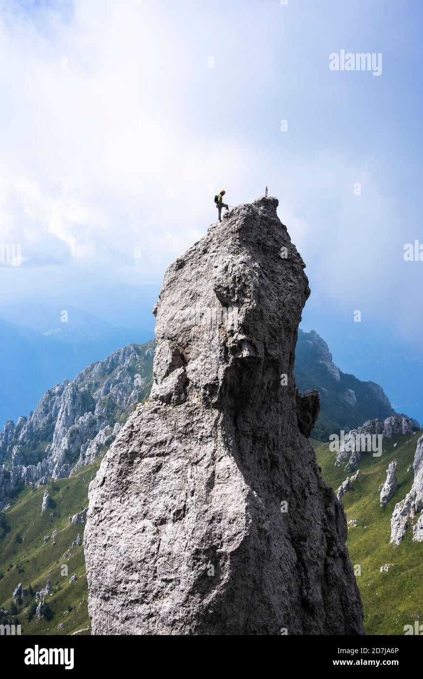 Männlicher Wanderer, der auf dem Gipfel des Berges gegen den Himmel steht, Europäische Alpen, Lecco, Italien Stockfoto