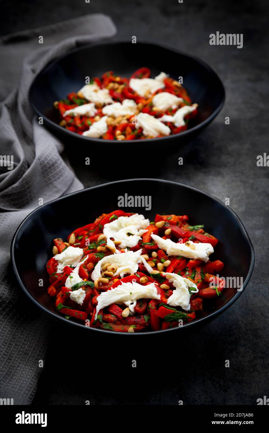 Zwei Schüsseln vegetarischer Salat mit roten Paprika, Mozzarella, gerösteten Pinienkernen, Petersilie und Schnittlauch Stockfoto