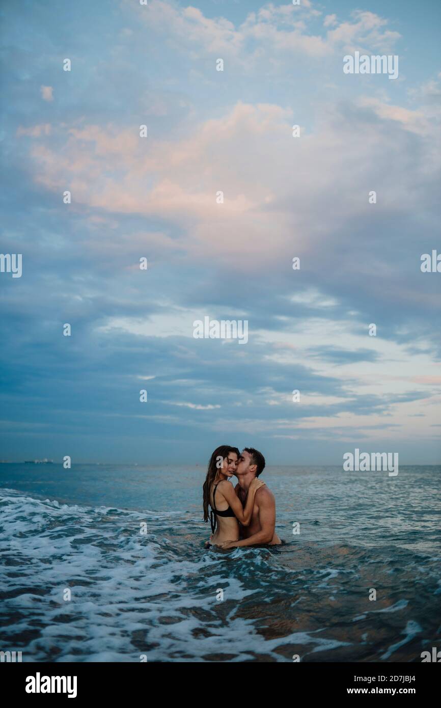 Ein Paar, das während des Sonnenuntergangs am Strand Romantik macht Stockfoto