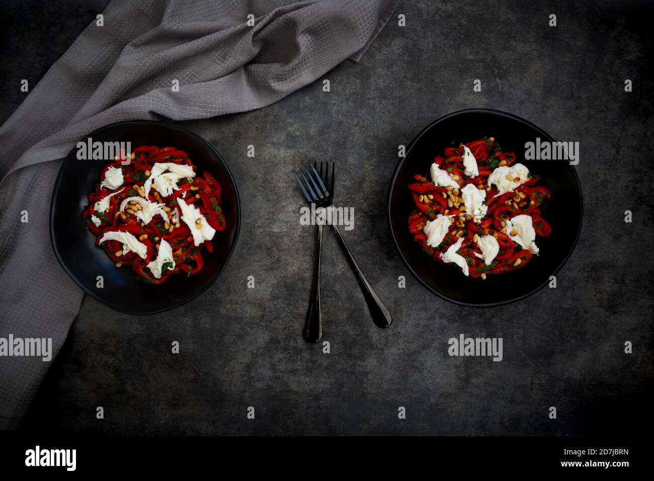 Zwei Schüsseln vegetarischer Salat mit roten Paprika, Mozzarella, gerösteten Pinienkernen, Petersilie und Schnittlauch Stockfoto