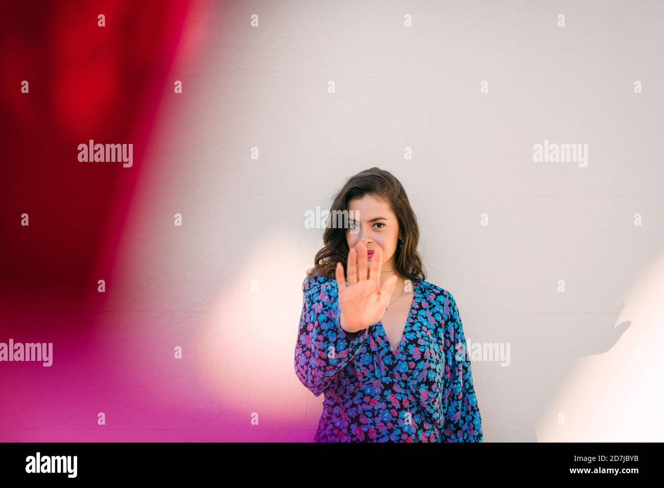 Junge Frau mit Stoppschild, während sie gegen die Wand steht Stockfoto