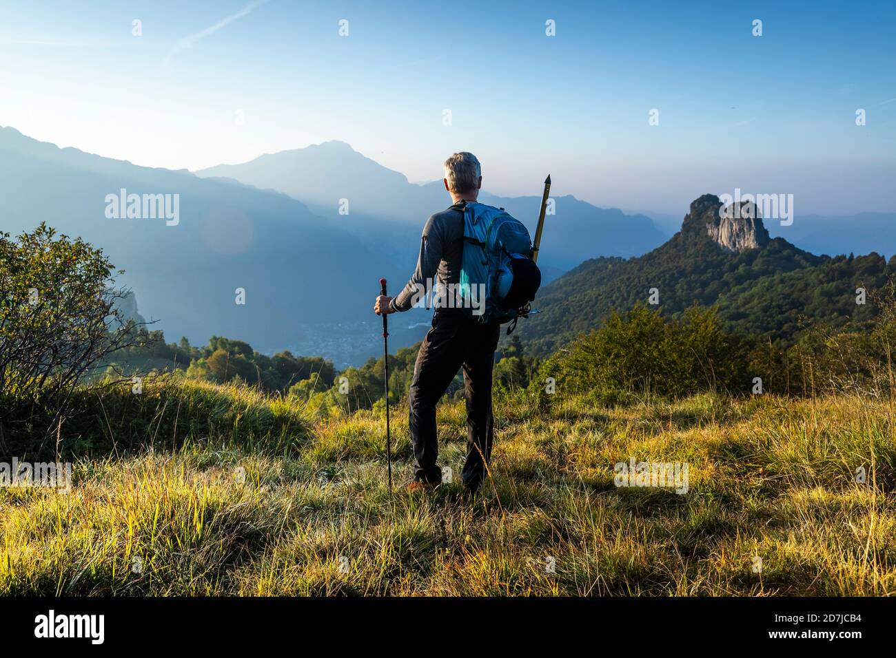 Männlicher Wanderer mit Rucksack mit Blick auf den Berg gegen den Himmel bei Sonnenaufgang, Orobie, Lecco, Italien Stockfoto