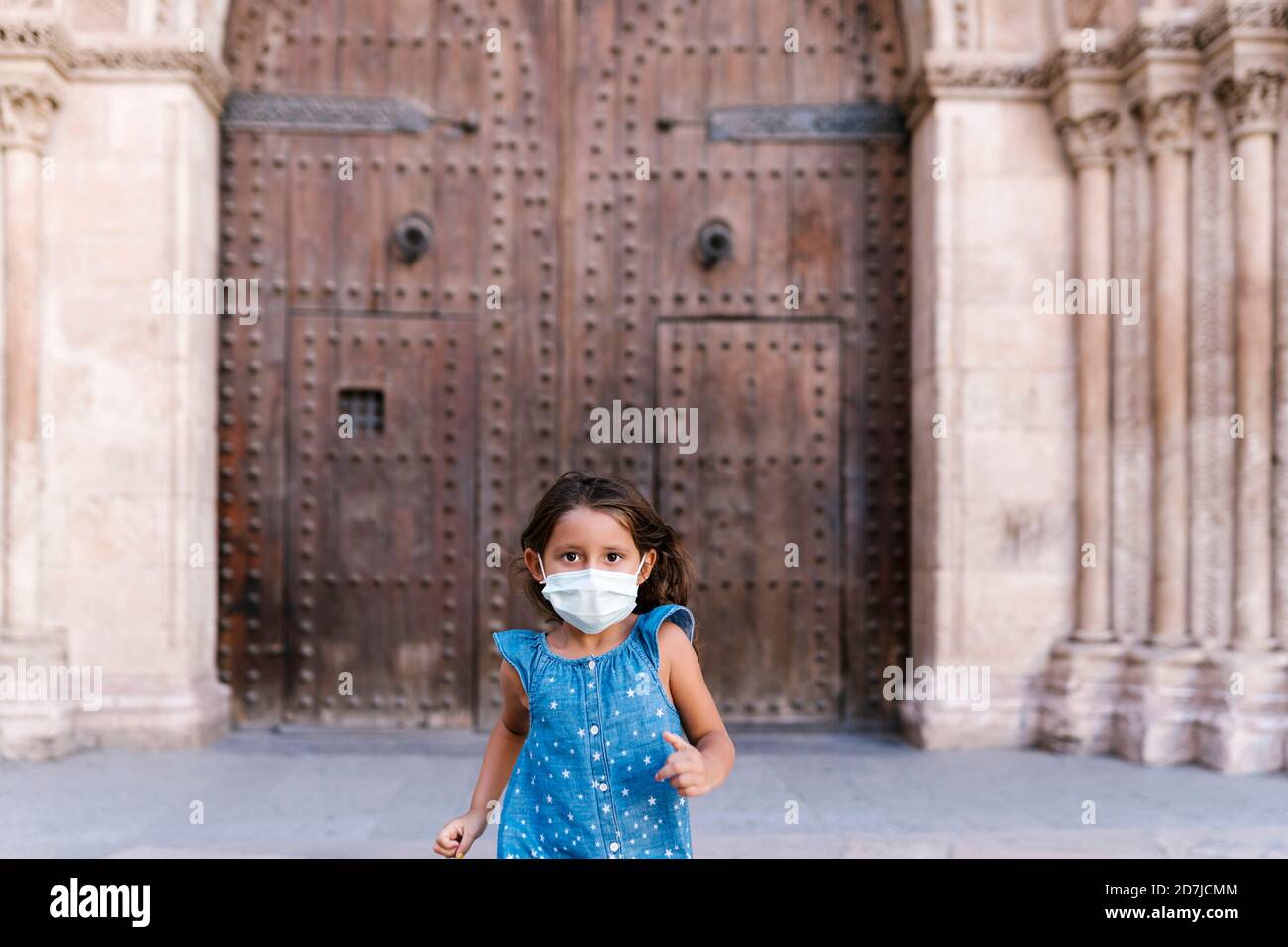 Mädchen trägt Maske läuft vor der historischen Tür Stockfoto