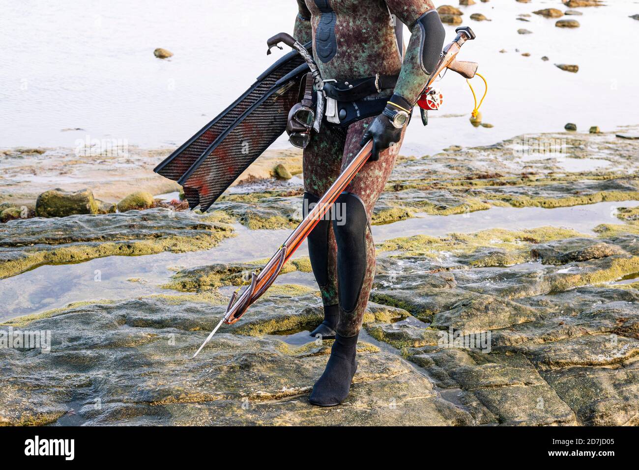 Reifer Mann, der Harpune hält, während er am Strand steht Stockfoto