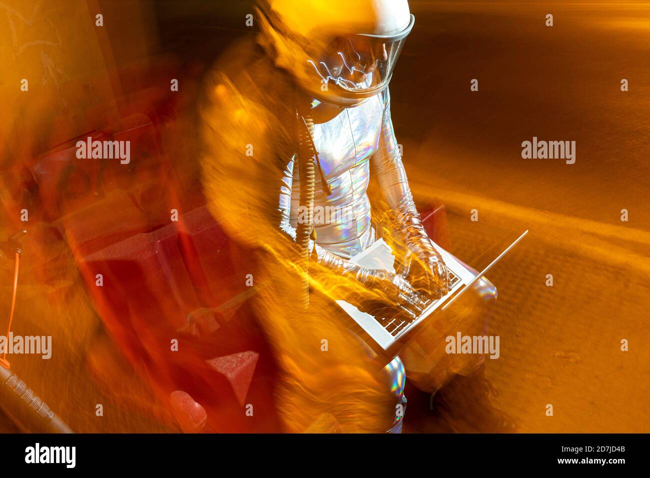 Männlicher Astronaut mit Laptop, während er im Freien sitzt Stockfoto