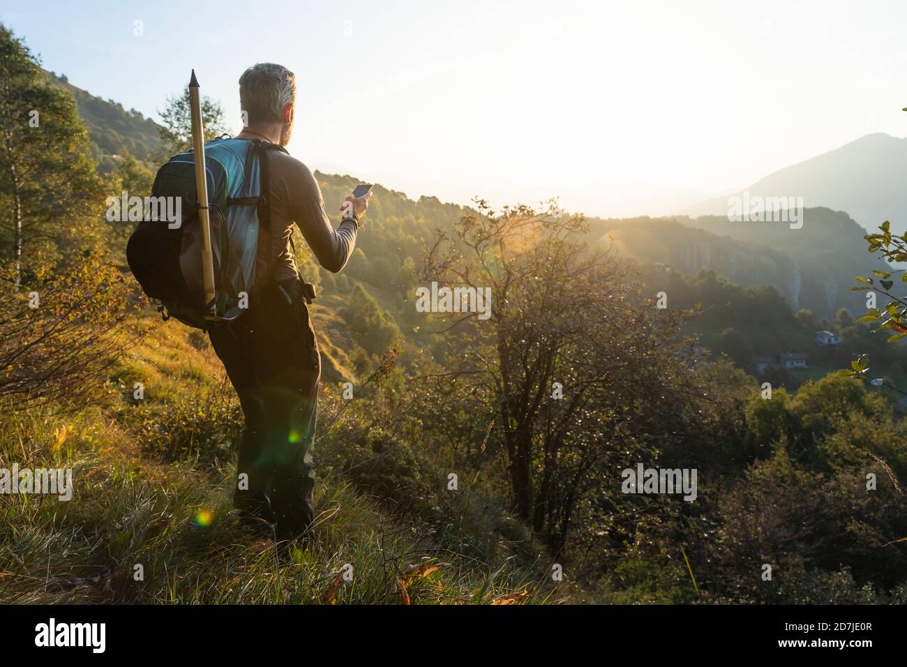 Reifer Mann mit Smartphone, während auf dem Berg bei Sonnenaufgang, Orobie, Lecco, Italien Stockfoto