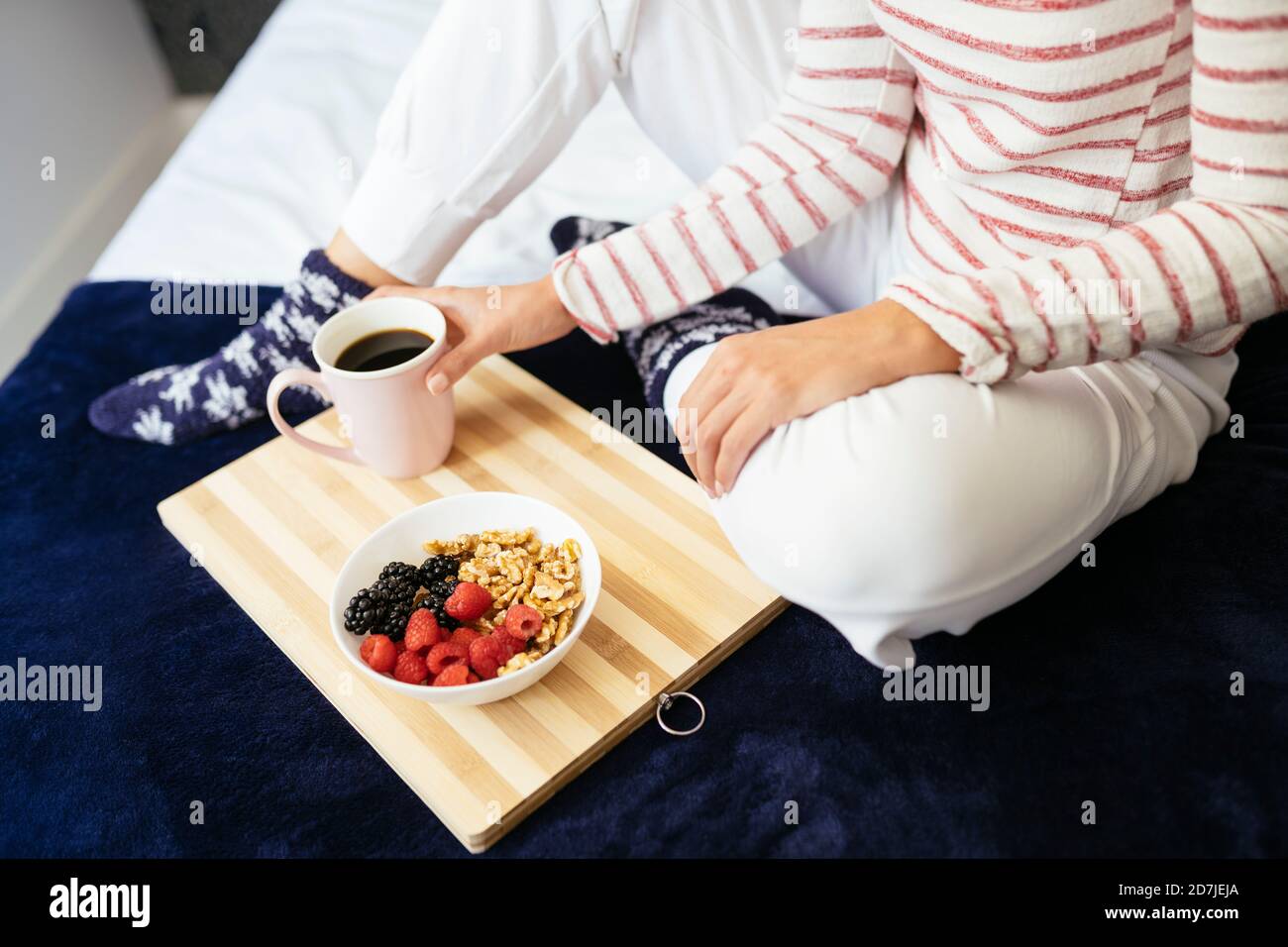 Frau sitzt mit Frühstück und Kaffee auf dem Bett zu Hause Stockfoto