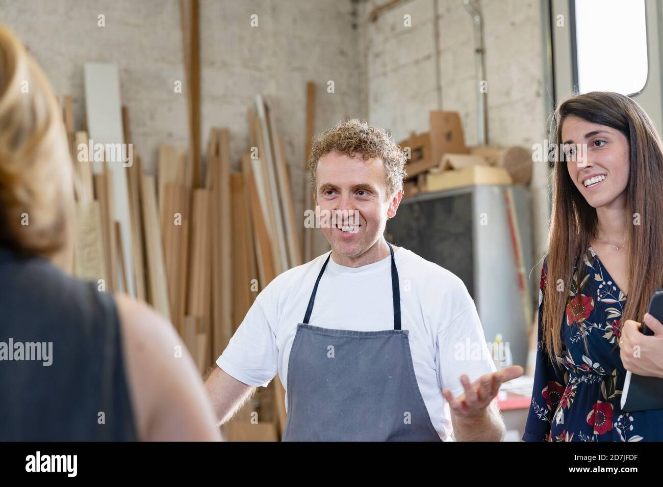 Lächelnder Mitarbeiter und Projektmanager, der im Stehen mit dem Mitarbeiter spricht In der Werkstatt Stockfoto