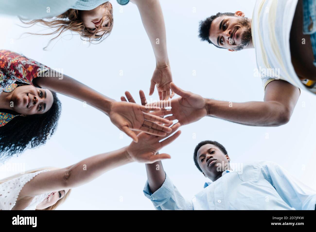Low-Angle-Ansicht von Freunden bringen ihre Hände zusammen in Zeigen der Einheit vor dem Spiel Stockfoto