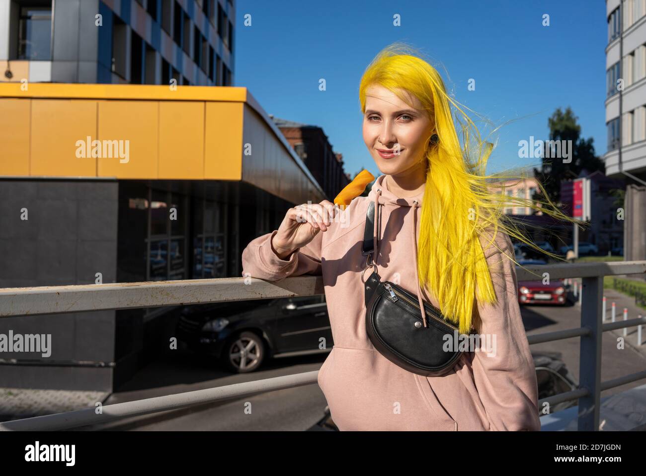 Gefärbte gelbe Haare Frau essen Eis, während Sie auf Brücke bei sonnigem Tag Stockfoto