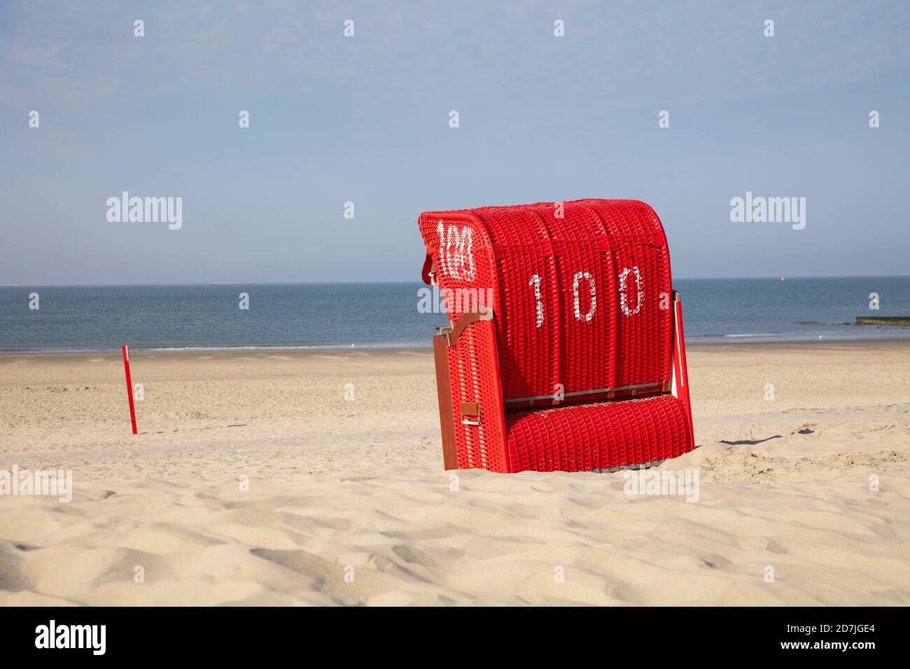 Roter Kapuzenstuhl am Sandstrand gegen blauen Himmel Stockfoto