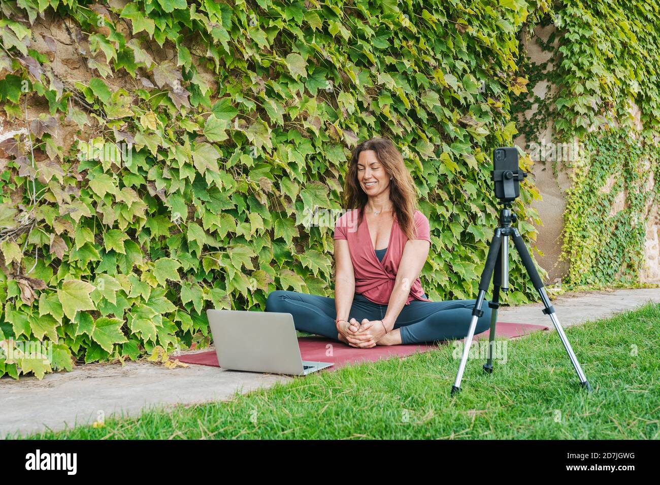Yoga-Lehrer Yoga in Online-Yoga-Klasse mit Handy unterrichten Telefon und Laptop Stockfoto