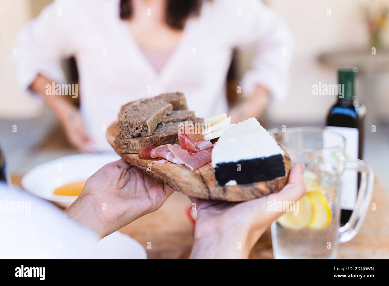 Frau hält den Teller, während sie am Esstisch sitzt Hinterhof Stockfoto