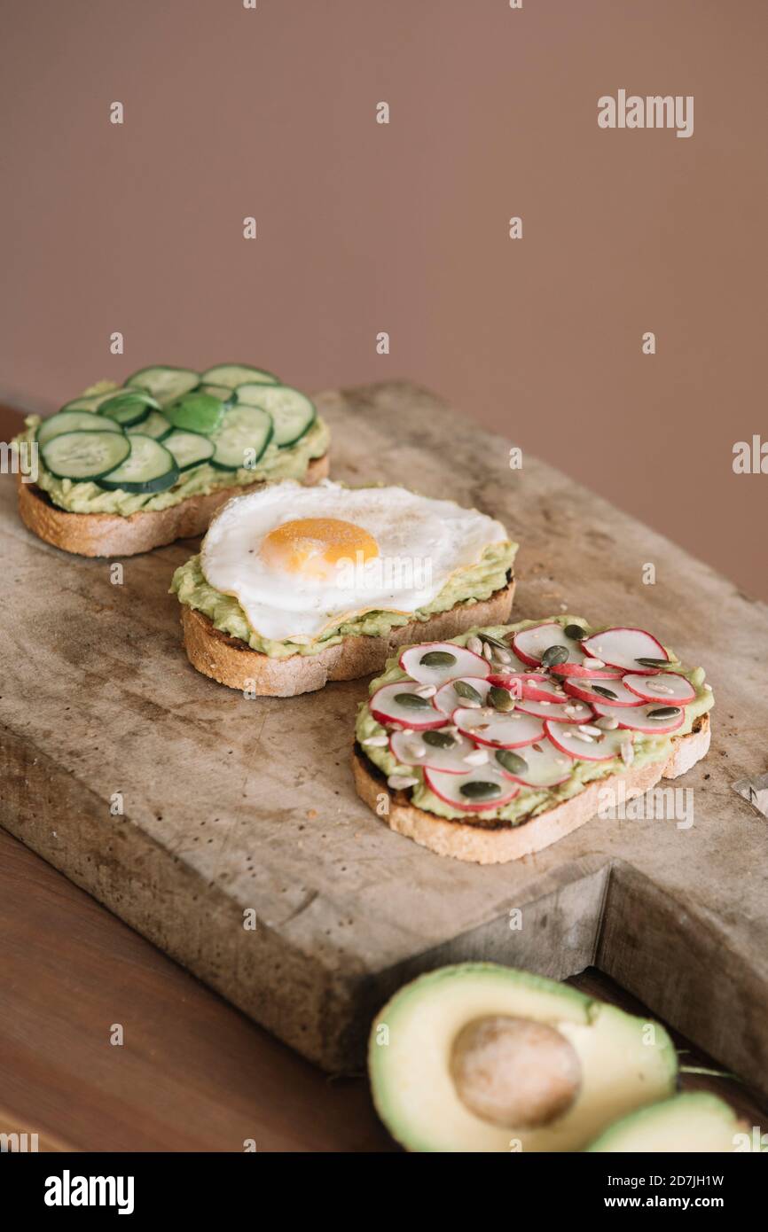 Brot garniert mit frischem Gemüse und Guacamole auf Servierplatte In der Küche Stockfoto