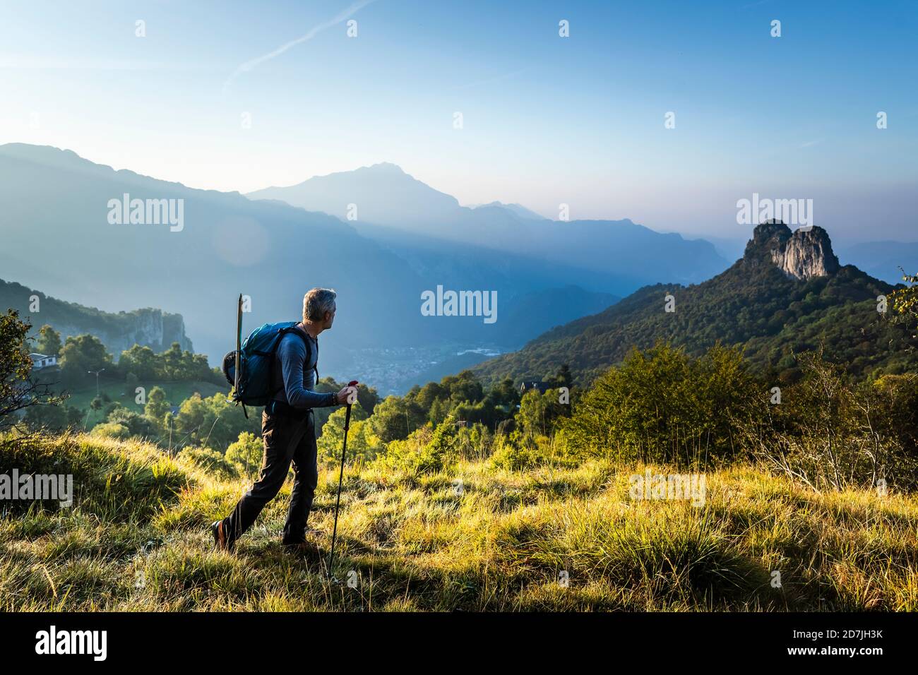 Männlicher Wanderer mit Pfahl, der bei Sonnenaufgang auf dem Berg gegen den Himmel läuft, Orobie, Lecco, Italien Stockfoto