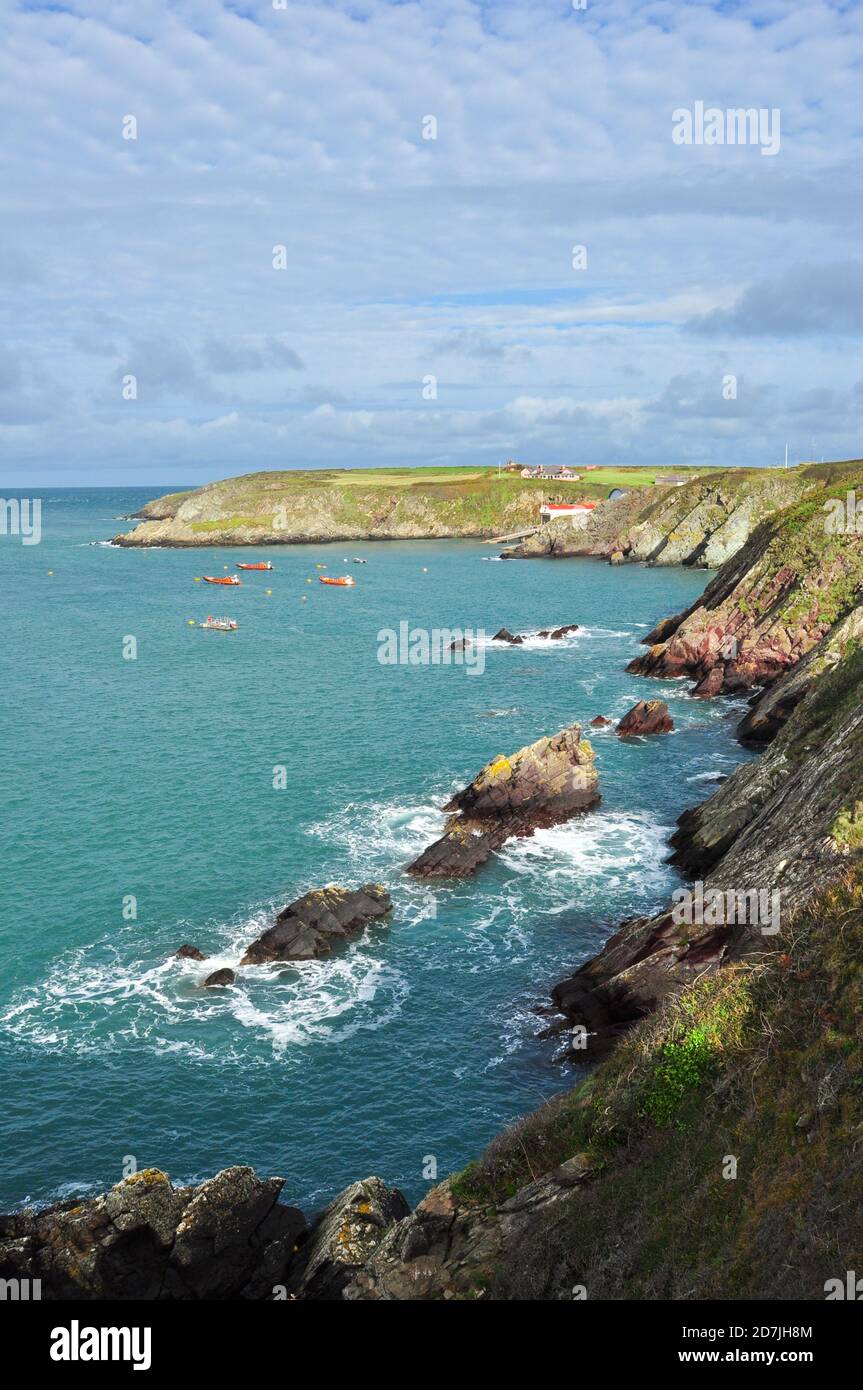 Zerklüftete Küste in St. Justinian's mit der Rettungsbootstation in der Ferne, Pembrokeshire, Wales, Großbritannien Stockfoto