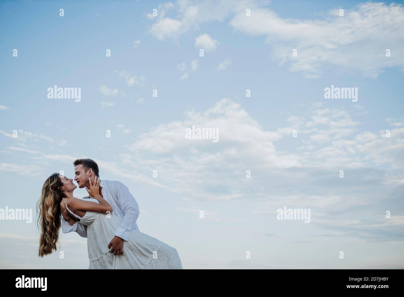 Junges Paar, das sich anschaut, während es gegen klar tanzt Himmel Stockfoto