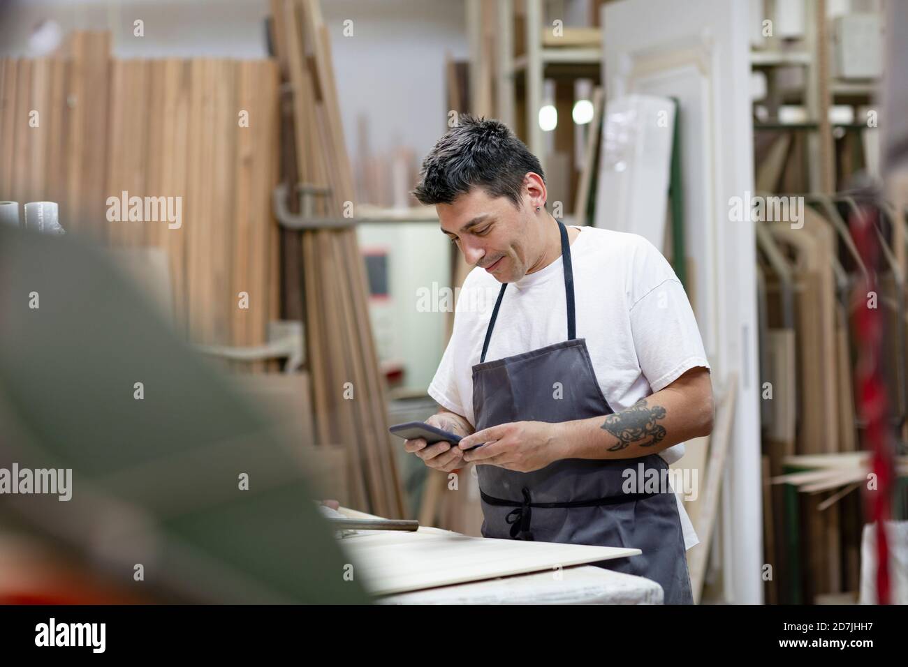 Männlicher Künstler mit Handy, während er in der Werkstatt steht Stockfoto