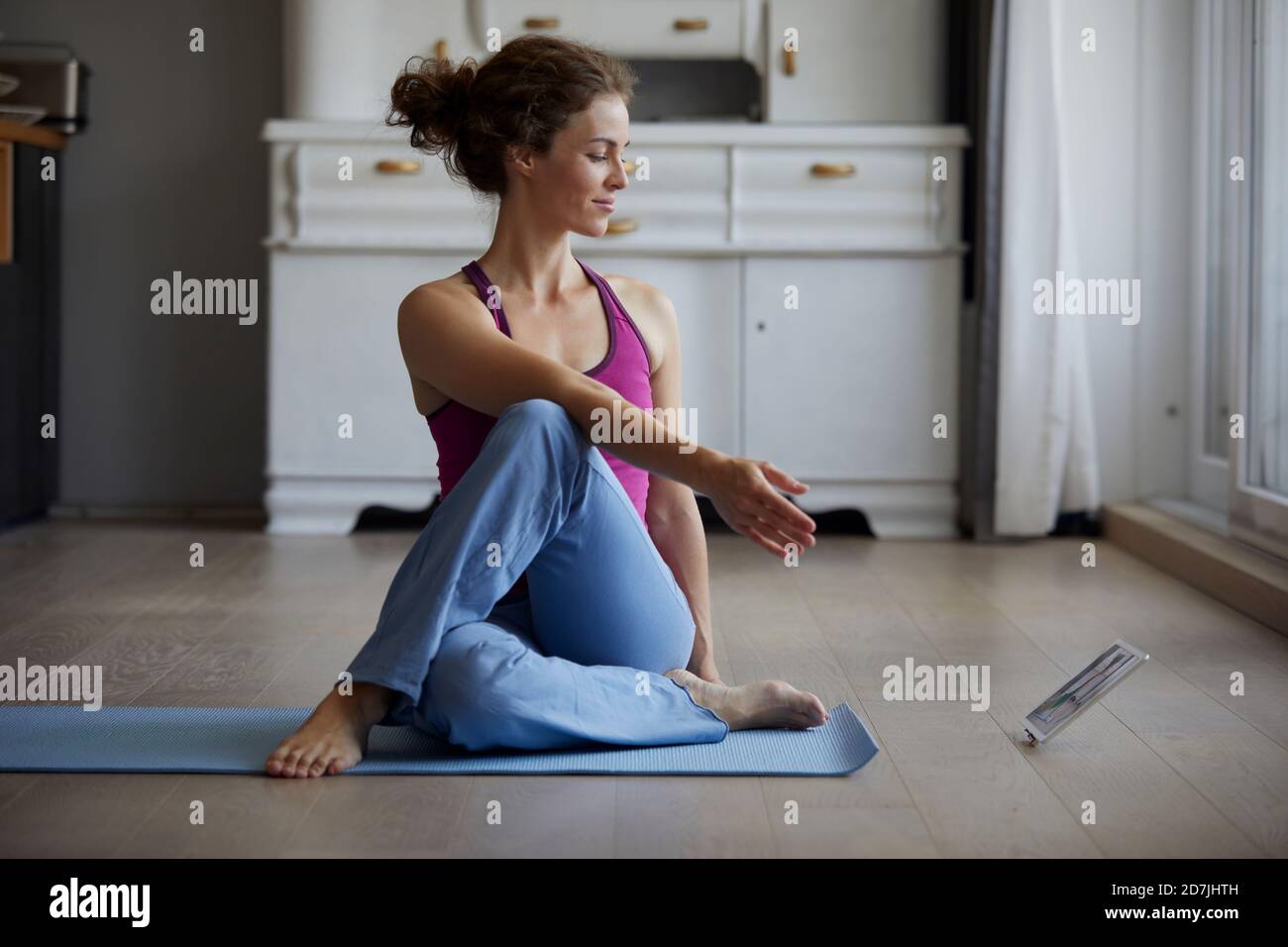 Frau, die sich ein digitales Tablet ansieht, während sie zu Hause Yoga praktiziert Stockfoto