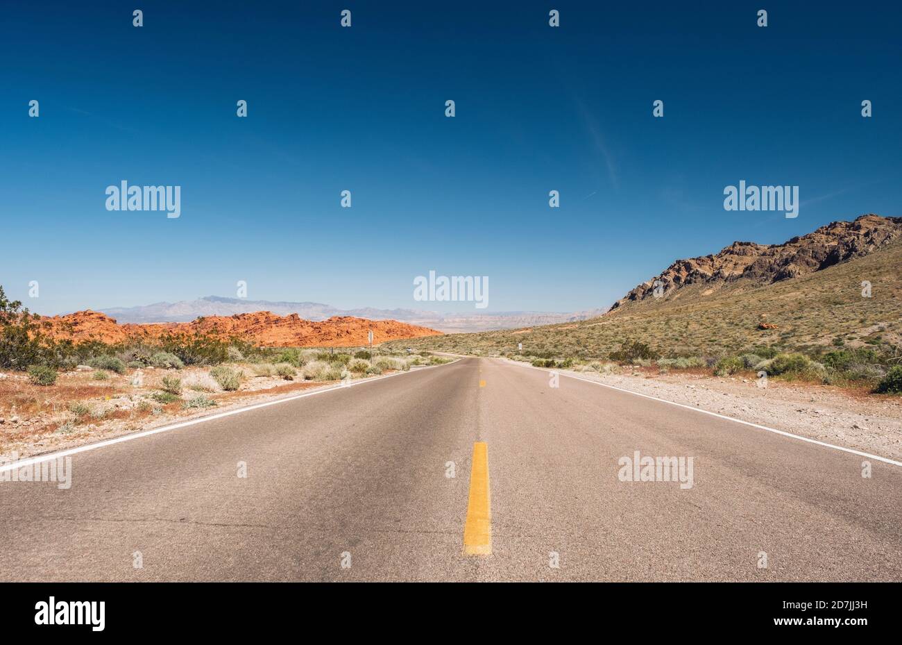 Abnehmende Ansicht der leeren Wüstenstraße gegen blauen Himmel, Nevada, USA Stockfoto